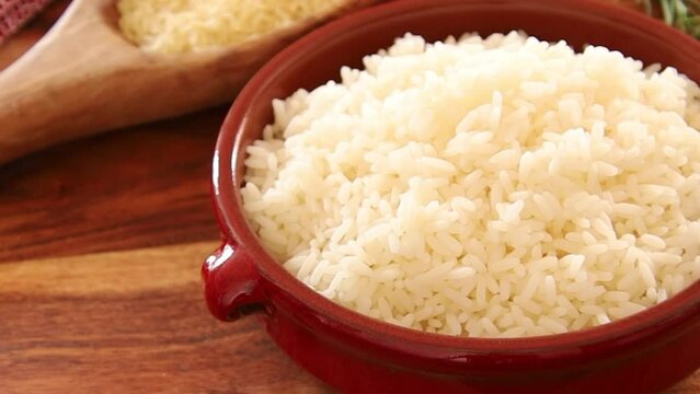 top view of raw and cooked rice in bowl on wooden background