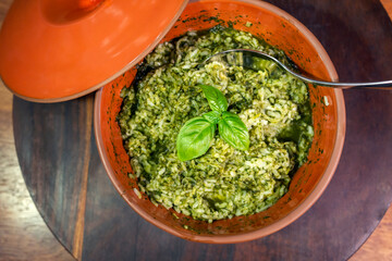 Traditional Italian risotto in an orange rustic pot. Pesto sauce.