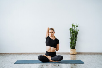 Portrait of a sports girl on a yoga mat. The girl is engaged in yoga, stretches the muscles of the arms and back. Taking care of your body and mind. Pacification