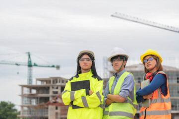 Young and senior Engineers discuss about work of large building underconstruction,Three people working on site of under construction