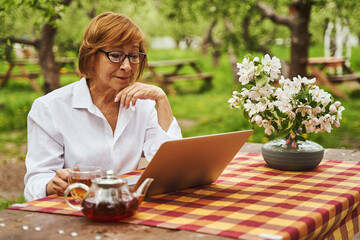 Happy female working online in spring garden