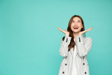 Young beautiful Asian woman surprise and look up at the empty space above isolated over green background, Thrilled excited concept