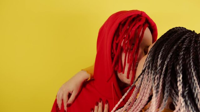 Young man with red dreadlocks in hood kisses unrecognizable woman. Handsome male kissing with love and embracing faceless female.