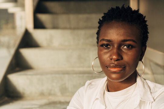 Close-up view of an African American woman looking at the camera with a serious expression on her face while posing on the stairs.