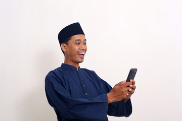 Surprised asian muslim man while looking cellular phone.