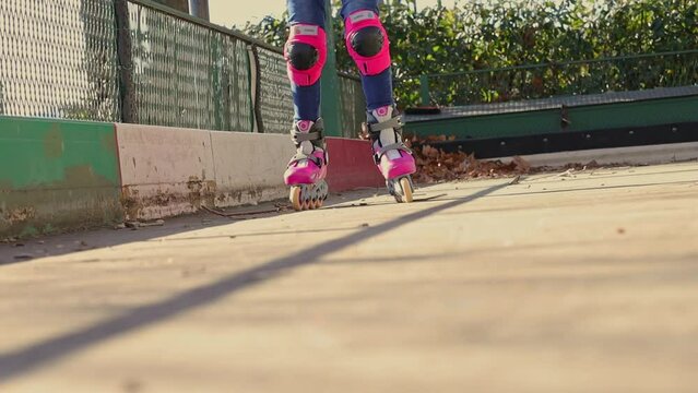 Close up of legs rides on roller skates. Little girl riding roller skates. Street sports concept. Roller skating training. High quality FullHD footage