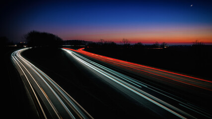 Autobahn bei Nacht mit Lichtspuren von Autos
