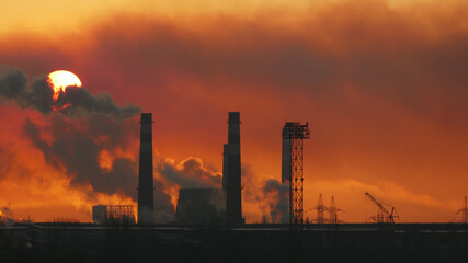 Silhouette of a metallurgical factory. Heavy industry at dawn. Global warming background. Air pollution concept.