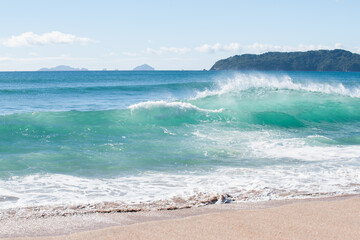 Surf waves crashing in on deserted beach at Tairua