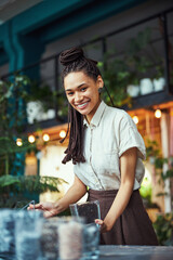 Smiling beautiful florist filling a florarium with soil