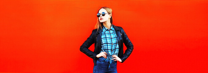 Portrait of stylish blonde young woman in black rock style on vivid background