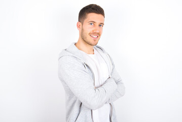 Image of cheerful young caucasian man wearing casual clothes over white background with arms crossed. Looking and smiling at the camera. Confidence concept.