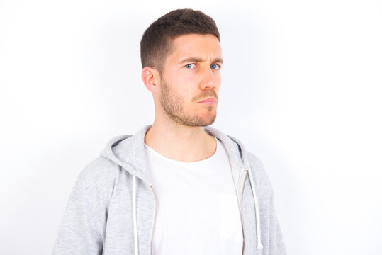 young caucasian man wearing casual clothes over white background with snobbish expression curving lips and raising eyebrows, looking with doubtful and skeptical expression, suspect and doubt.