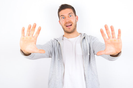 Dissatisfied young caucasian man wearing casual clothes over white background frowns face, has disgusting expression, shows tongue, expresses non compliance, irritated with somebody.