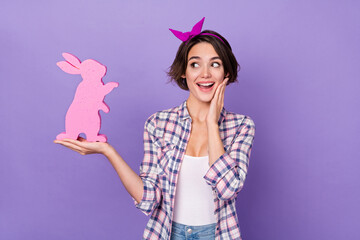 Photo of pretty impressed lady dressed checkered shirt holding looking pink hare isolated purple color background