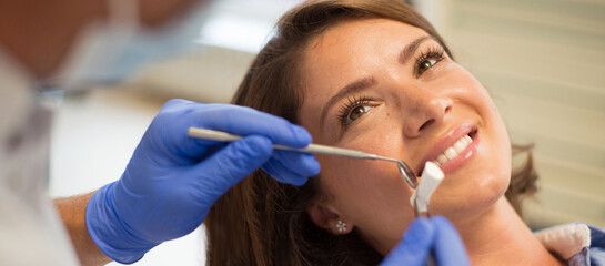 Young woman checking her teeth at the dentist clinic