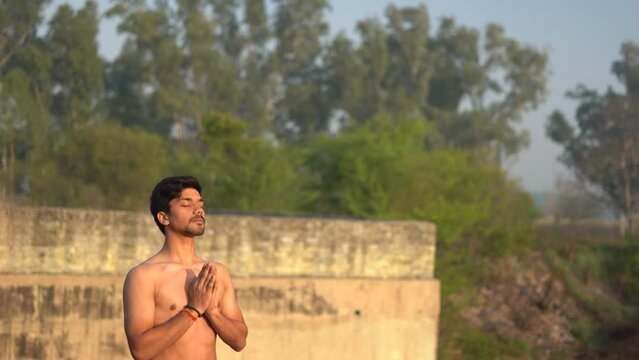 Young Indian boy praying to god early in the morning in sunrise. Worshiping to hindu god in india.