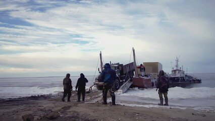 People stand in the cold and watch the shipment of the liver. CLIP. They brought a large car and ship it to the shore. At the end, caterpillar vehicles come to the fore