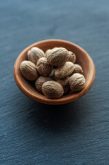 whole nutmeg, spices, ingredients, on a black background, in a wooden bowl, top view, space for text