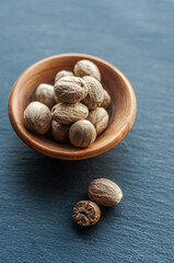 whole nutmeg, spices, ingredients, on a black background, in a wooden bowl, top view, space for text