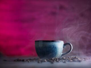Ceramic blue coffee cup smoke. Roasted coffee beans, pink dark background