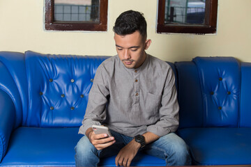 Young handsome man using smatphone when sitting on sofa
