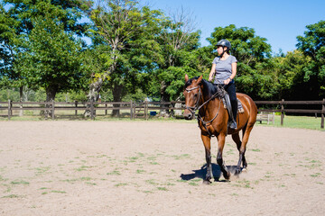 young latina woman practicing horseback riding in the countryside, copy space