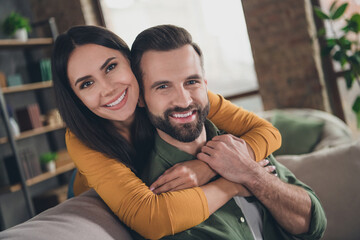 Portrait of attractive cheerful couple hugging spending vacation sitting on sofa having fun at home house flat indoors