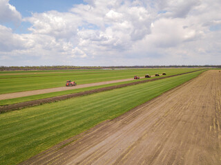 Aerial drone photo. Agriculture machienary cultivates green rolled lawn.