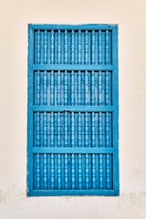 Closed window with typical blue wooden bars in beige building in old colonial city of Trinidad,Cuba
