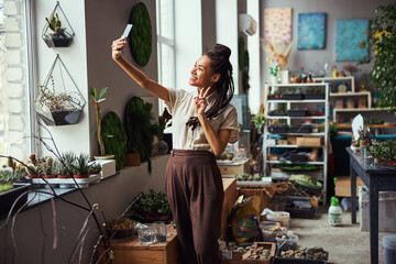 Cute dark-haired joyful florist taking a selfie with a smartphone