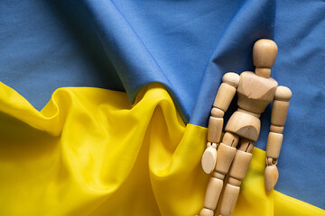 Yellow and blue national flag of Ukraine as background and wooden man, stop war and peace in Ukraine