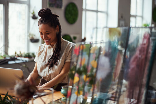 Florist with a happy smile typing on the laptop