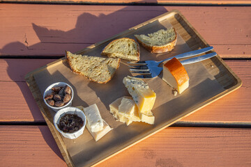 Dutch snack platter with 2 forks, bread, cheese and nuts in direct sunlight