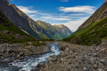 Norwegian landscape, a view of the mountains, a mountain stream flows below, and the mountain slopes are covered with grass and shrubs