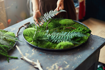 Florist adding a fern frond to other plants on a platter