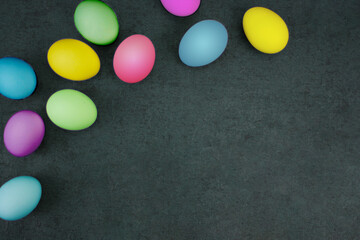 Fototapeta na wymiar Pastel Colored Easter Eggs Holiday Border Pattern Over Black Paper Background Texture with Copy Space Shot from Directly Above