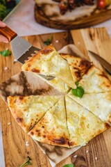 Traditional georgian cuisine of Khachapuri with suluguni cheese, served on the light table with spice and wooden spatula