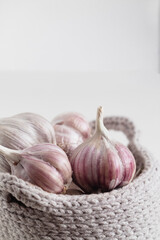 Crochet basket with organic garlic bulbs on a white background.