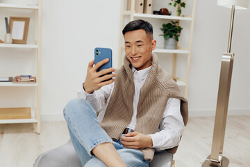 teenager sitting in a chair in a room with phone on his lap