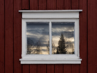 Evening landscape reflected in the window of a red barn.