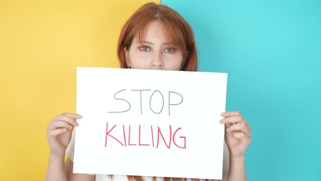A beautiful red-haired ukrainian woman says Stop killing in the colors of ukrain