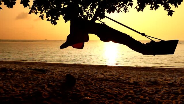 Man standing at the wooden swings riding to the one side. Slow motion of the swing ride at the ocean coast. Concept of the travelling and journey at the vacation at Thailand beach of the ocean.