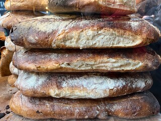 Close up of stack of large flat loaves, the freshly baked hot bread with brown crisp crust and soft centre displayed on food stall at Borough Market in the South Bank in London UK