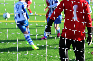 Boys soccer game where the goalkeeper is seen in the spotlight with some players