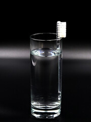 Toothbrush in a glass of water on black background