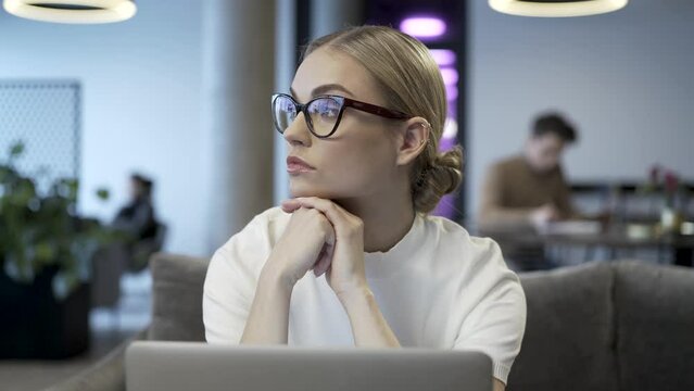 Thoughtful concerned young and attractive business lady is sitting and looking away to the horizon while thinking about her work problems and future decisions.