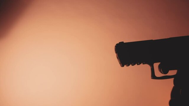 Silhouette of a hand gun coming into view and pulling the trigger