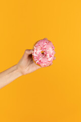 Fototapeta na wymiar Holding Strawberry Frosted Donut with Sprinkles