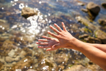 Hands of a man and a woman with wedding rings on the background of the sea. Close-up. Wedding concept